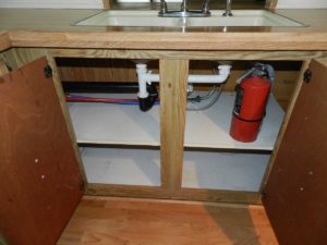 The area under a mobile home sink in kitchen
