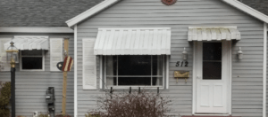 A gray mobile home with white metal mobile home awnings
