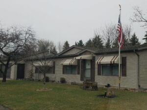 A brown doublewide with an American flag in the yard