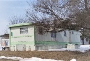 A green old mobile home singlewide