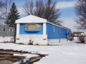 A blue singlewide metal mobile home