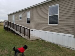 A brown mobile home with a dog out front