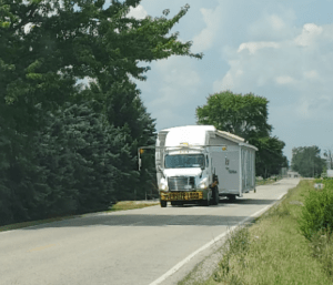 A singlewide mobile home being toted down the road
