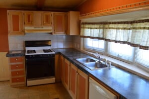 A small kitchen in a mobile home with curtains