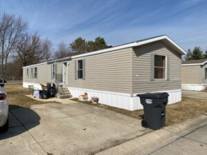 A singlewide with brown mobile home siding on a lot
