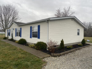 A doublewide mobile home with shrubs on each side