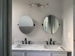 2 oval mirrors on a wall above a double sink