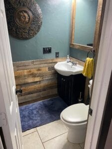 A bluish green wall in a bathroom with wood wall covering