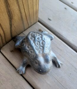 A cast iron frog sitting on a deck