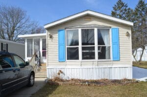 A singlewide mobile home with light blue shutters