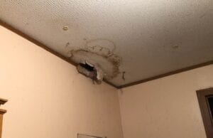 A hole in the drywall in a ceiling caused by water