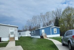 A bright blue mobile home with a long sidewalk