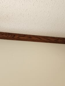 A wall that meets a ceiling with a brown trim board