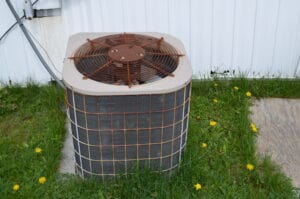 A rusted ac condenser unit sitting in grass
