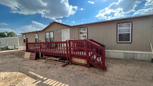 Doublewide mobile home with a large red deck out front