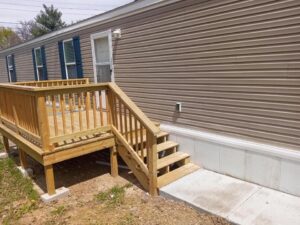 A large wooden deck on the side of a mobile home