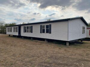 A large doublewide mobile home with white siding and black trim