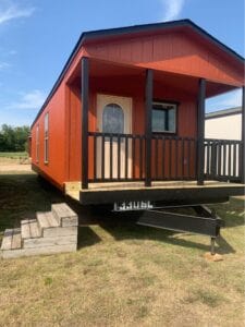 A tiny home for sale texas with red siding on land