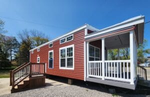 A red tiny home with a large white deck