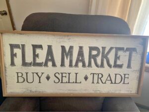 A wooden sign that says flea market buy sell trade