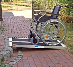A wheelchair going up a ramp with a brick sidewalk