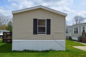 A yellow singlewide mobile home with white skirting