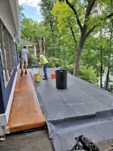 2 guys installing rubber roofing on a home