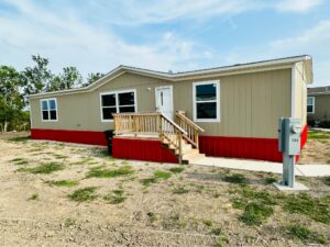 A doublewide with red skirting on land