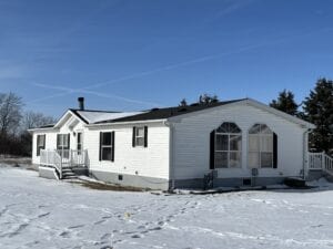 A doublewide mobile home with snow on the ground and on the roof