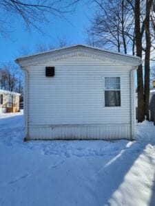 A trailer home with snow on the ground and on the roof