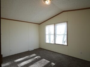 A bedroom with a window and white curtains