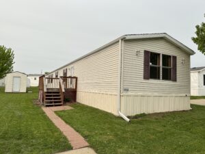 A trailer home sitting on green crash with a small walkway up to it