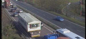 A singlewide mobile home going down a highway