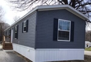 A dark gray sided mobile home with black shutters