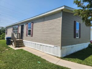 A brown doublewide manufactured home with a walk