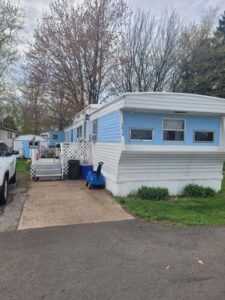 A light blue striped mobile home with metal siding