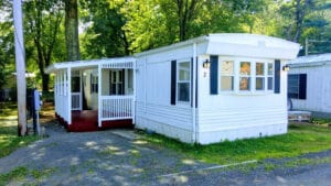 A vintage 1970s mobile home with white siding