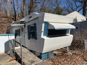 An antique singlewide with white metal siding