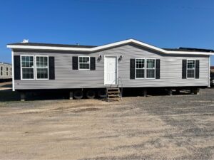 A gray doublewide with no grass out front just dirt