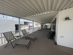 A white carport with a deck built into it with chairs