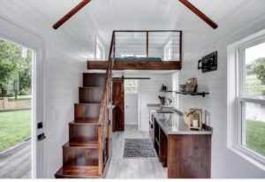 A white room with a kitchen and a stairs going up