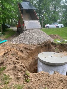 A dump truck dropping rock near a new septic tank