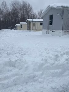 A pile of snow in front of 4 mobile homes