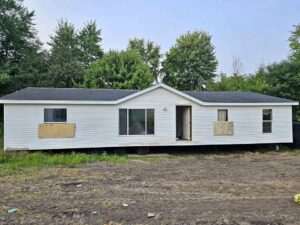 A doublewide mobile home with boarded up windows