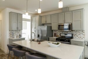 A gray kitchen with pendant lights hanging