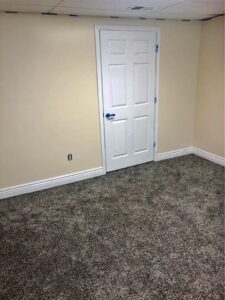 A cream colored room with a white door and carpet