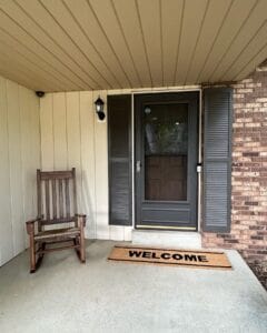 A rocking chair and a welcome mat by a door