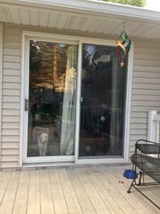 A sliding glass door with brown siding