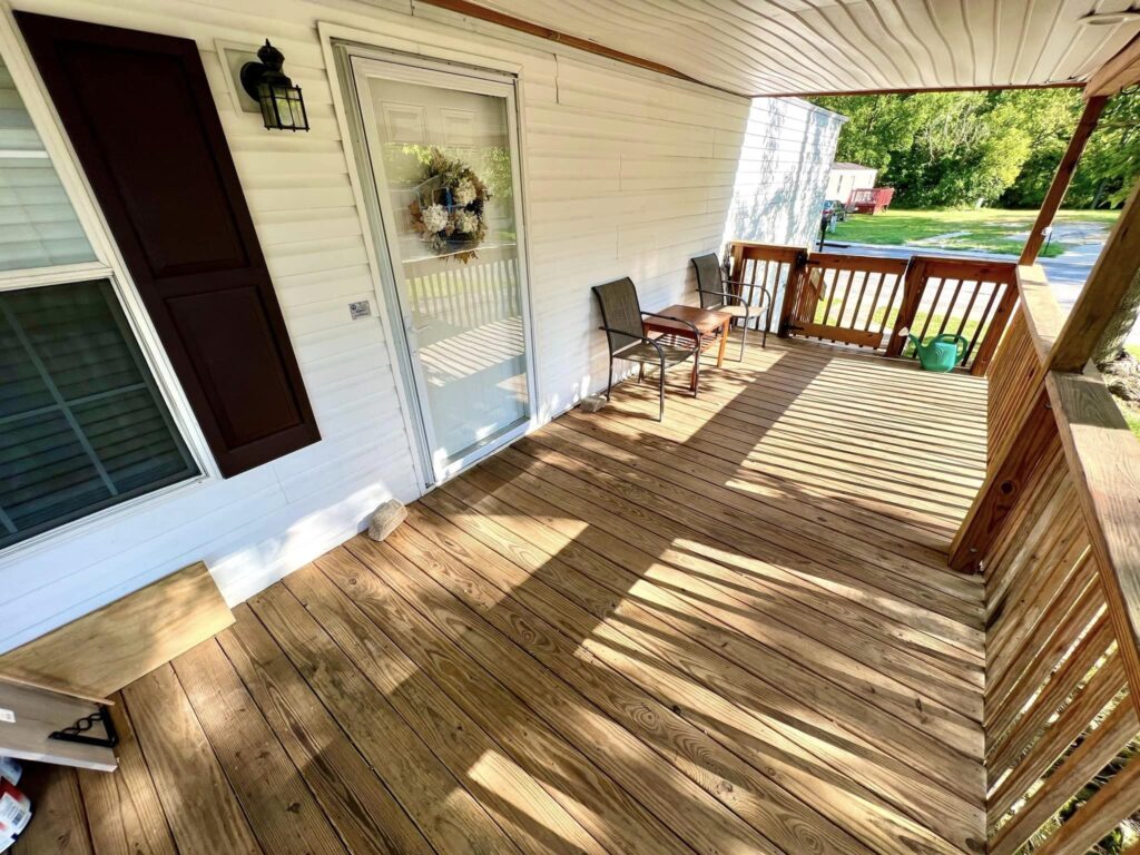 A wood deck on the side of a white mobile home
