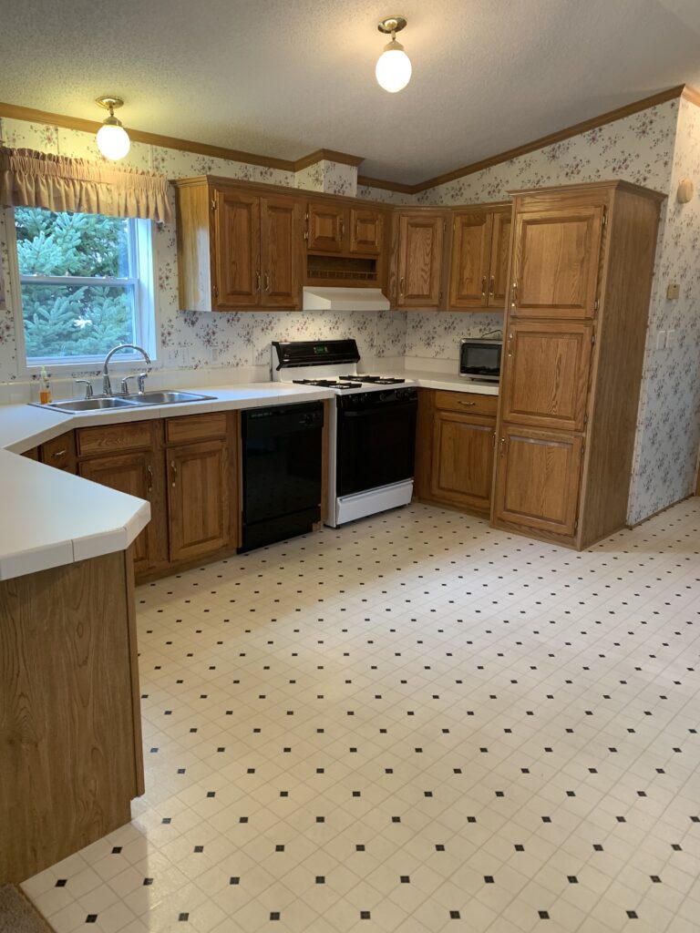 The view of a kitchen in a mobile home with honey colored oak cupboards